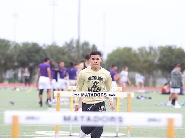 high school student at track practice doing hurdles
