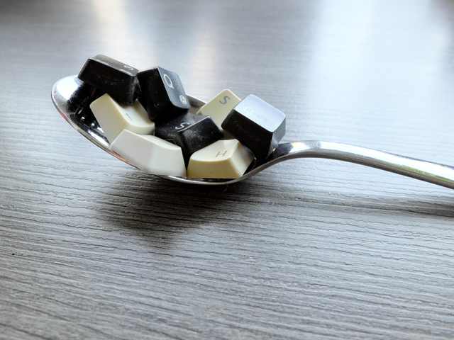 Black and white computer keyboard keys on the spoon to feed the computer model.