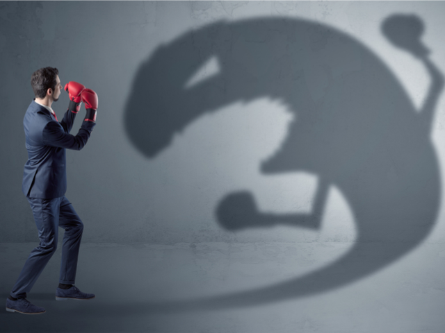 A businessman wearing boxing gloves sparring with a big monster shadow - rogue chatbot concept