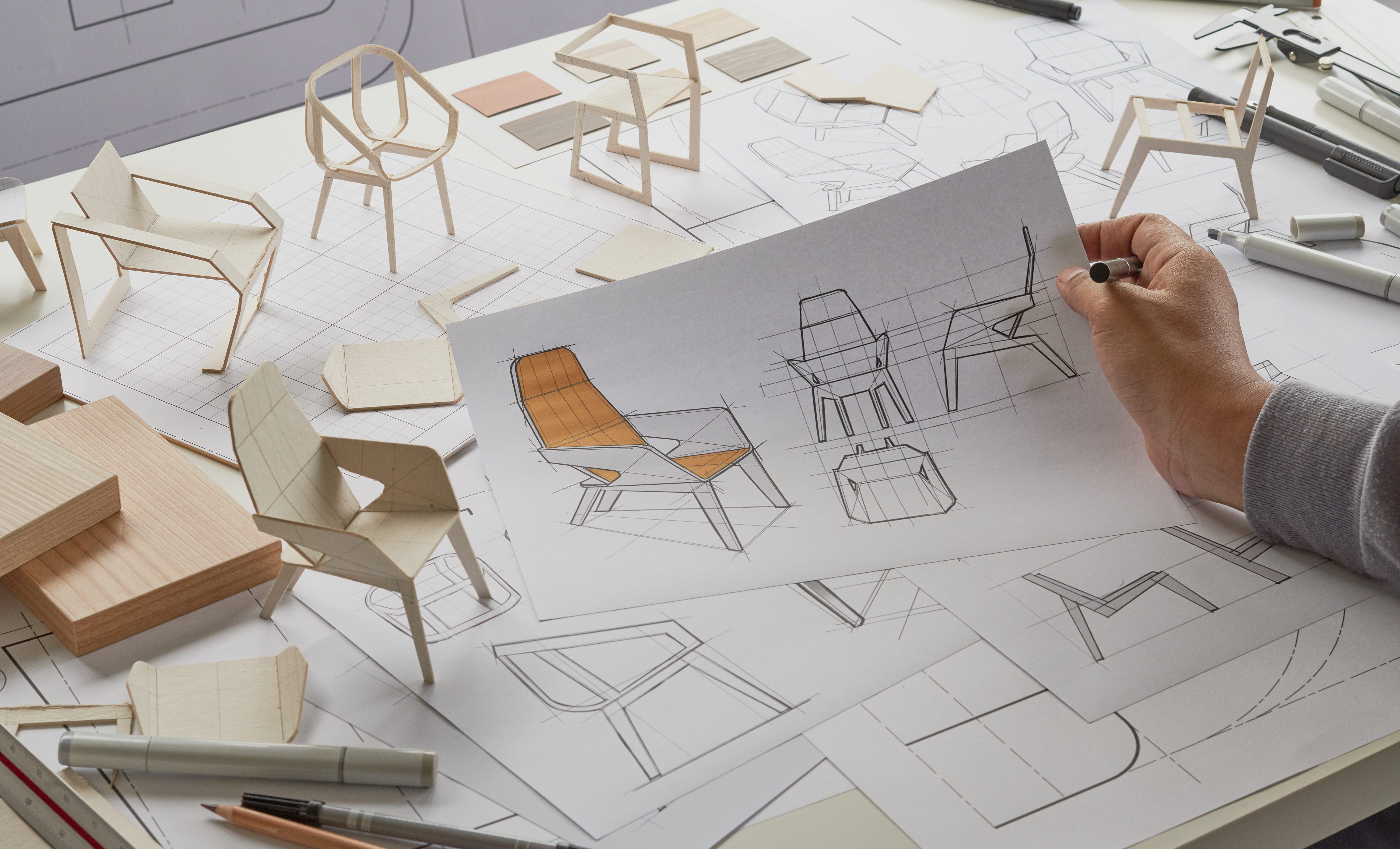 A person looking at diagrams and models of chairs