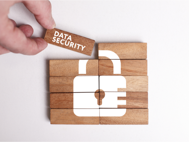 wooden blocks pushed together to create a picture of a white lock. One block says data security - workplace data security concept