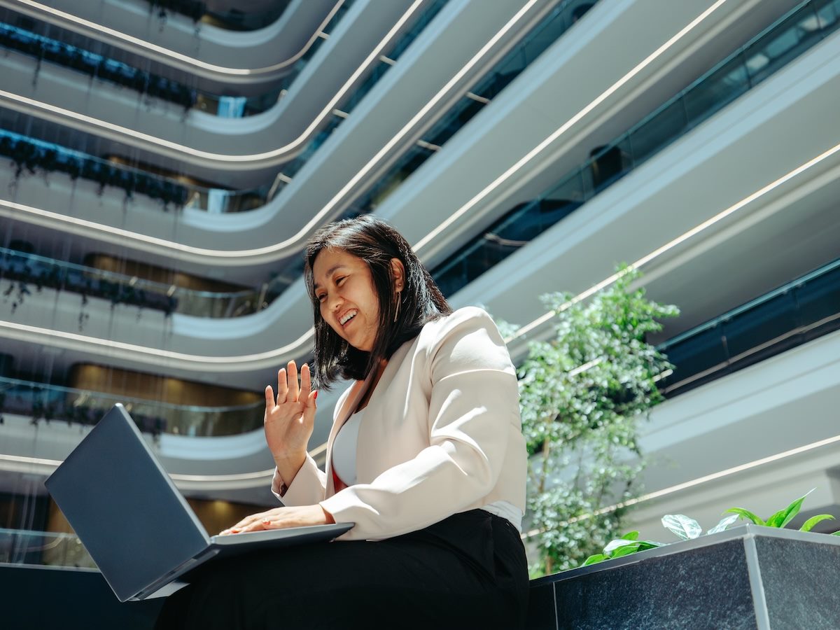woman waving into a laptop during an online meeting