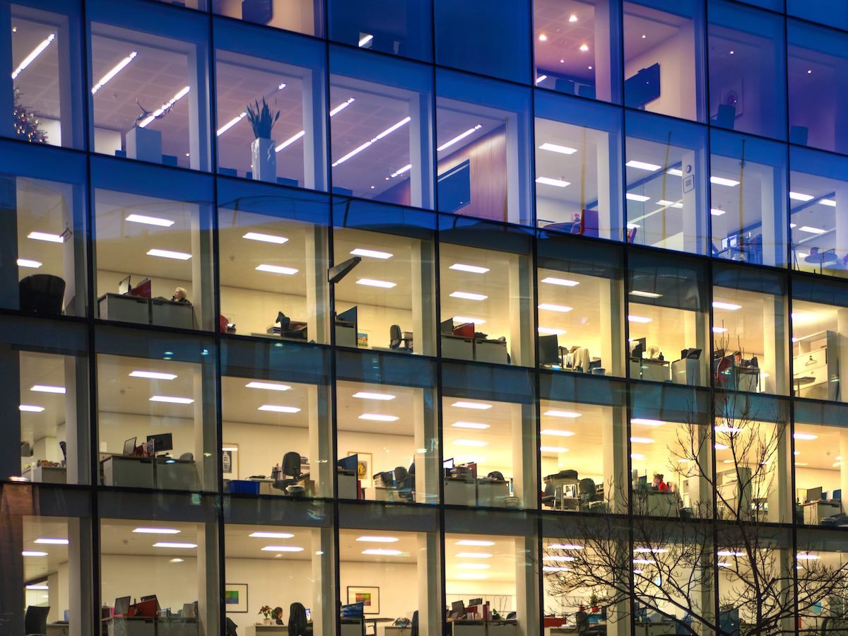 Outside view of a lit-up, glass office building at night 
