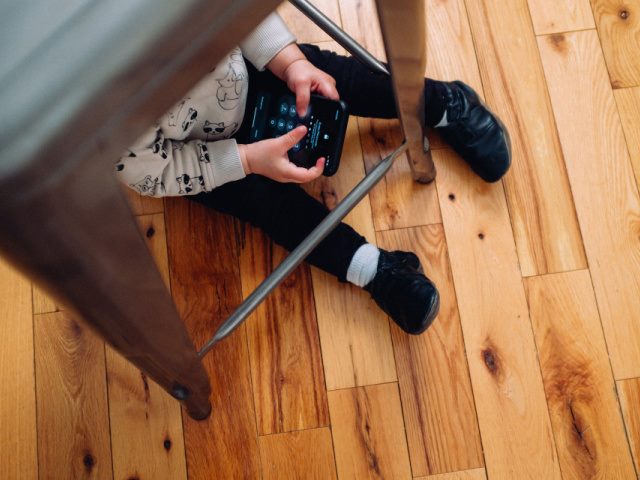 child sitting under stool a mobile phone