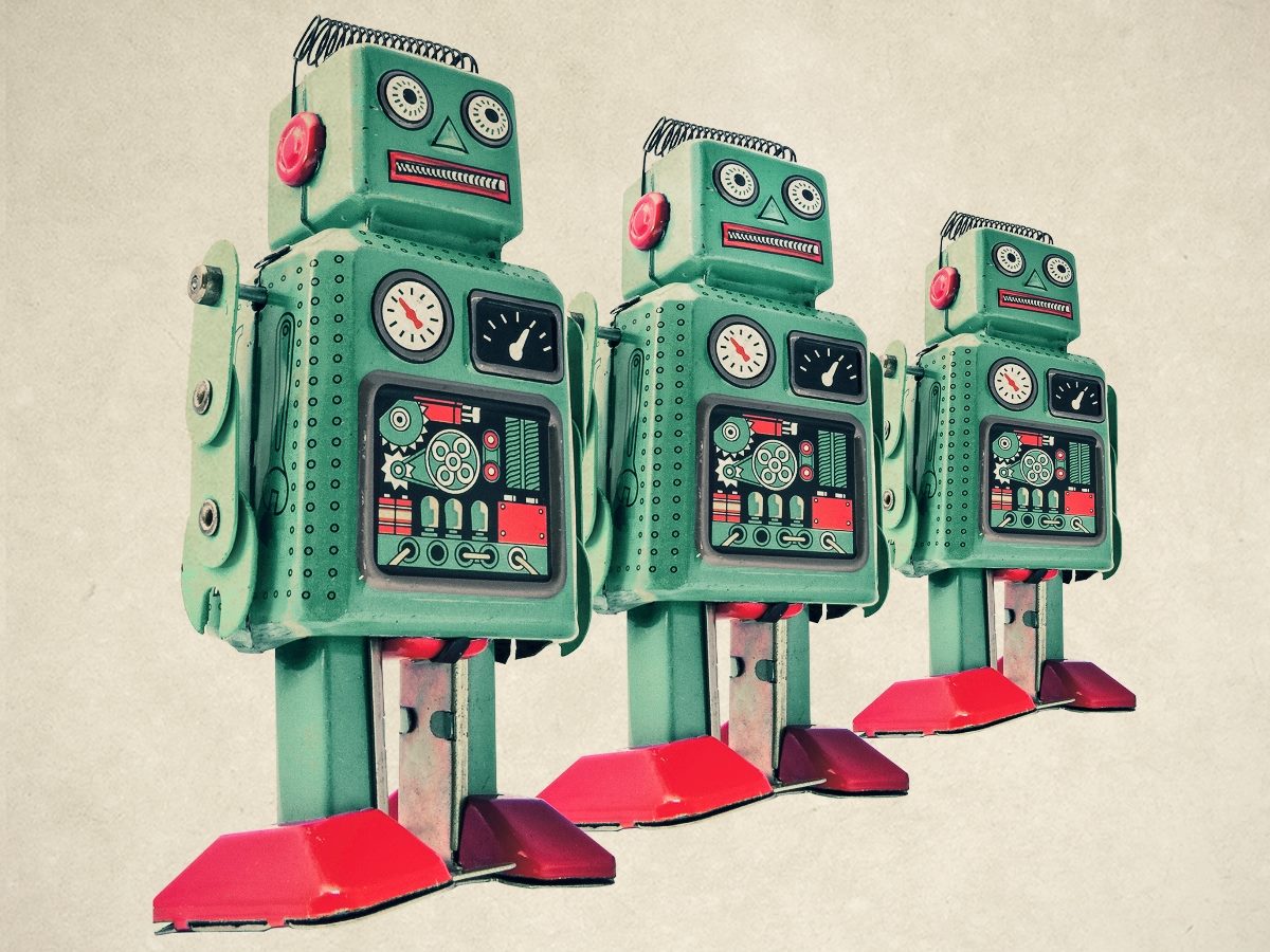 Vintage-style illustration of three retro toy robots standing in a row from largest to smallest against a neutral beige background. The robots are teal with red feet and buttons, featuring clock-like dials, mechanical chest panels and whimsical mid-century design details.