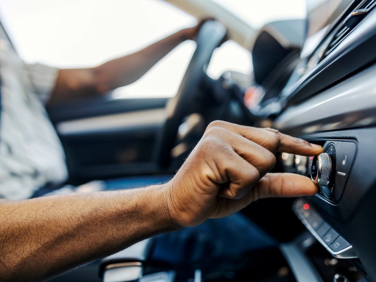 Close-up of a driver adjusting a car’s volume knob on the dashboard, illustrating how buyers are tuning out excessive noise and seeking more control.