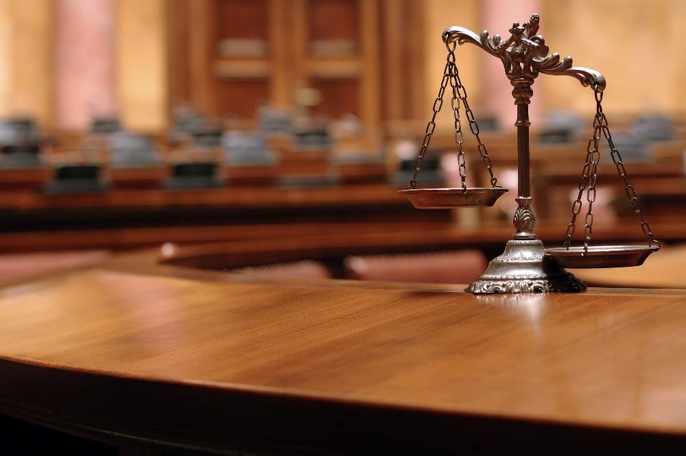 Decorative metal scales of justice sitting on a wooden table in a courtroom in piece about AI content management strategy.