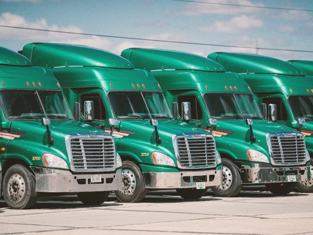 A group of semi-trucks parked in a parking lot.