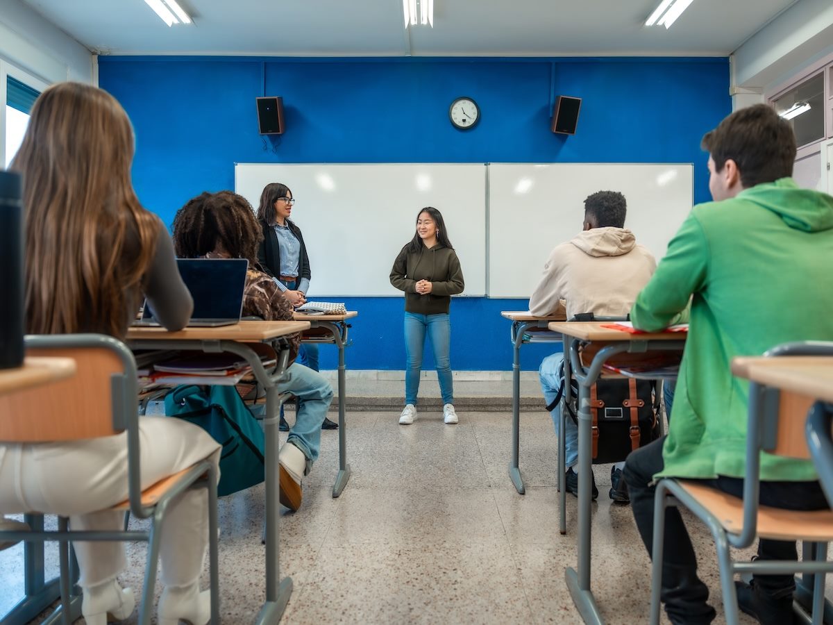 High school student giving presentation to classmates and teacher