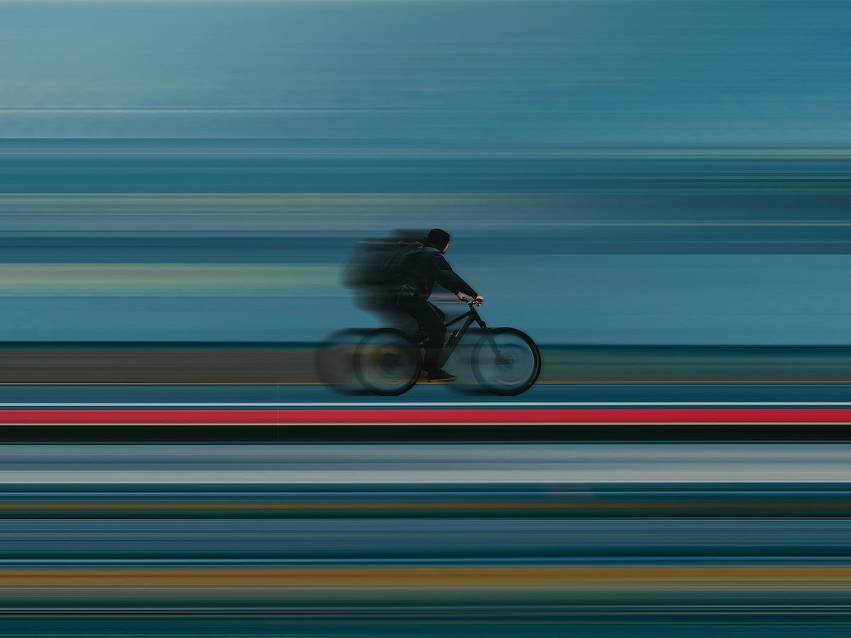 stop motion photo of a speeding bicyclist. colorful lines below denote the speed