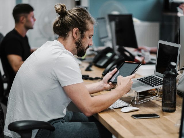 An employee works on a tablet at a desk in an office.