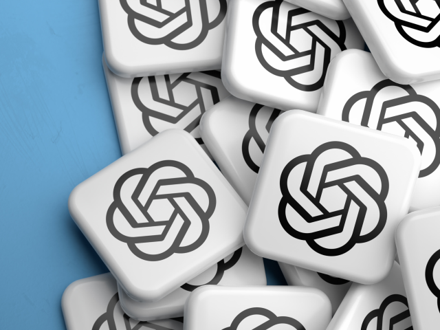 A pile of scrabble tiles with the OpenAI logo on them on a blue tabletop.