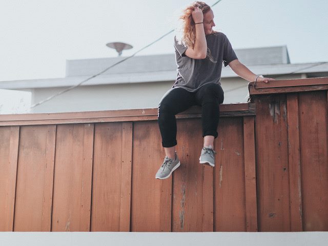 young woman sitting on a fence