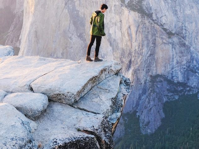 person looking over  the edge of a cliff