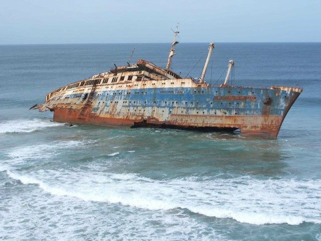 abandoned, rusted ship resting in shallow waters.