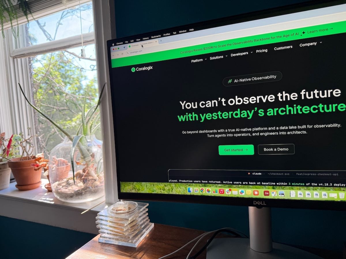 Coralogix home page on a large monitor, plants and window behind