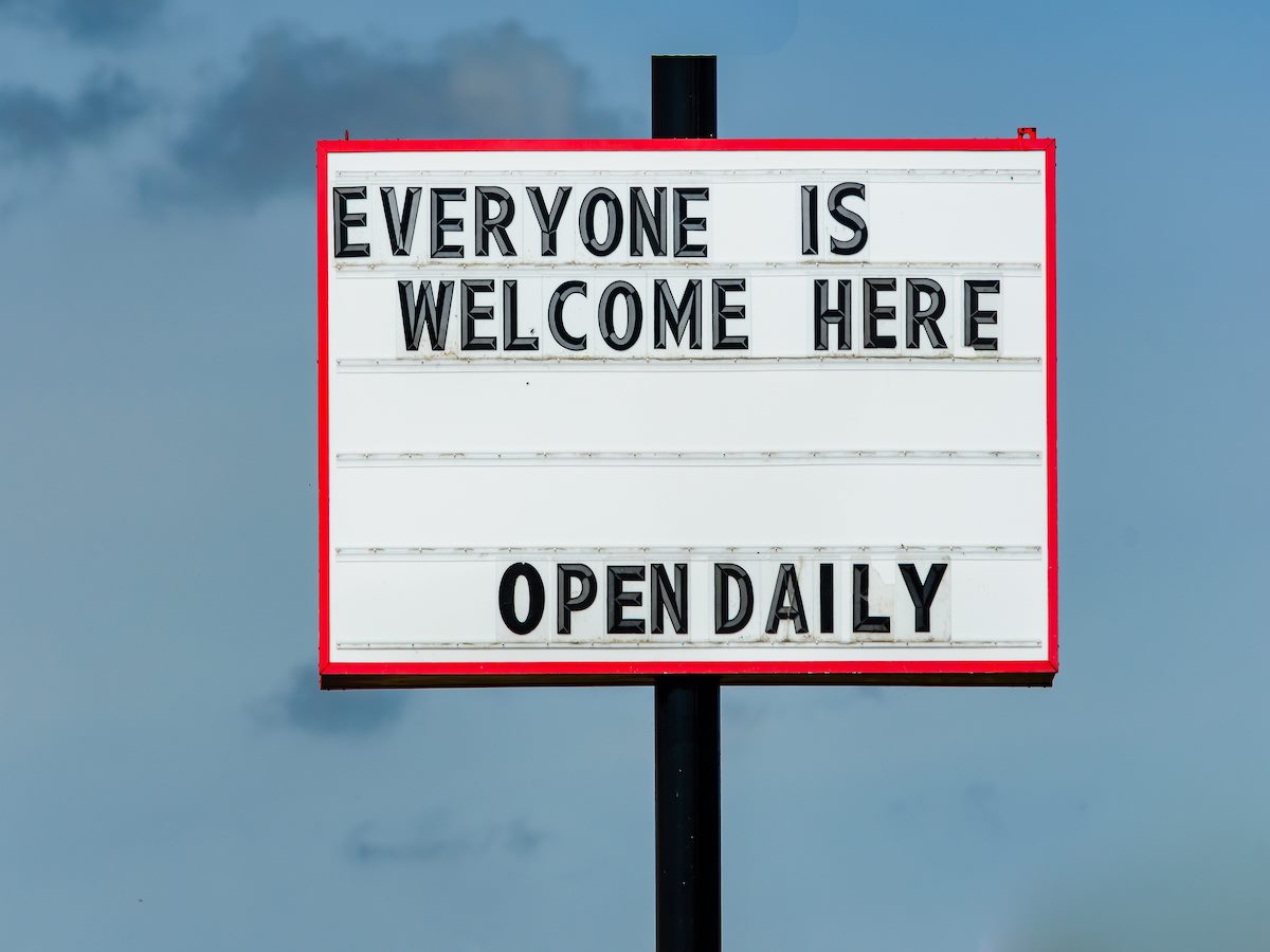 A large outdoor sign that says "Everyone is welcome here, open daily"