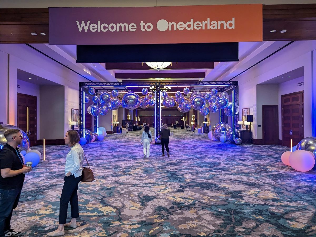 Conference-goers in a hallway at Optimizel's Opticon conference in San Antonio in November 2025. A big sign above says, "Onederland."