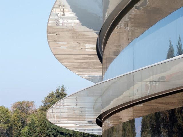 A view of windows at the Apple Park building with trees in the background.