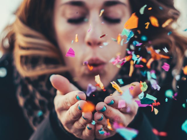 woman blowing colorful confetti out of her hands