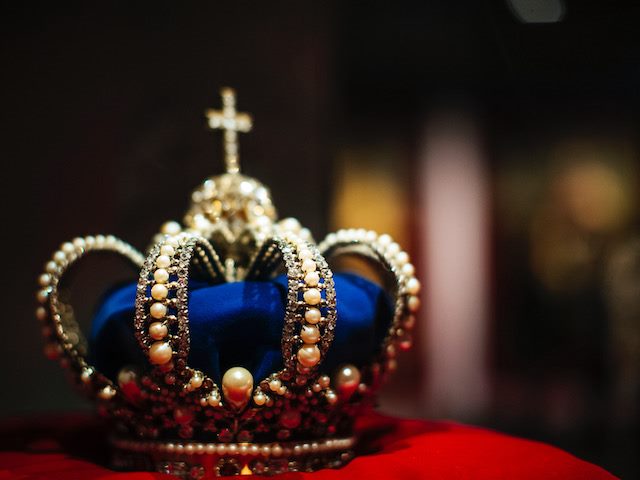 blue and gold crown on a red velvet pilow
