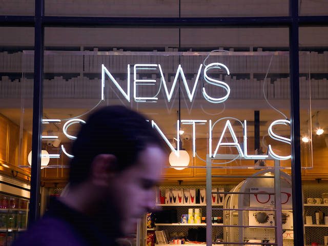 man walking past neon sign that says "NEWS"