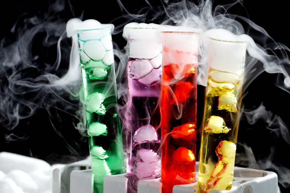 Four large test tubes filled with red, purple, green and yellow liquid and smoke pouring from the top sit on a table in piece about AI Marketing Tools and experimentation.