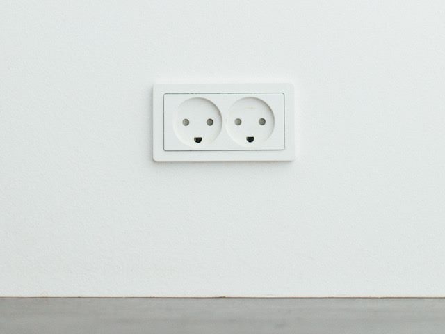 two european wall outlets next to each other looking like two smiling faces, pareidolia