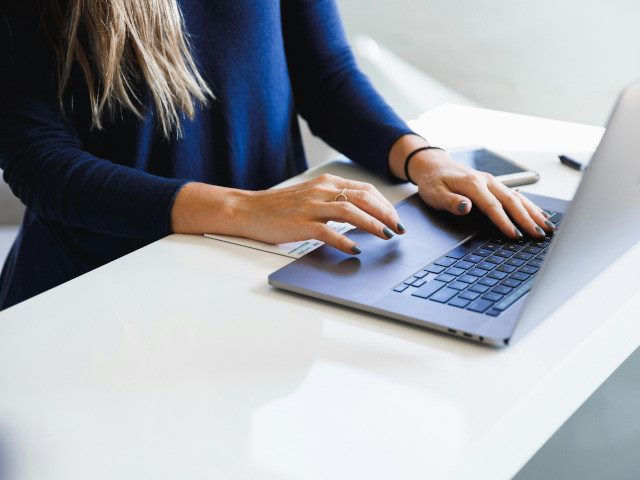 An employee works on a laptop on a desk.