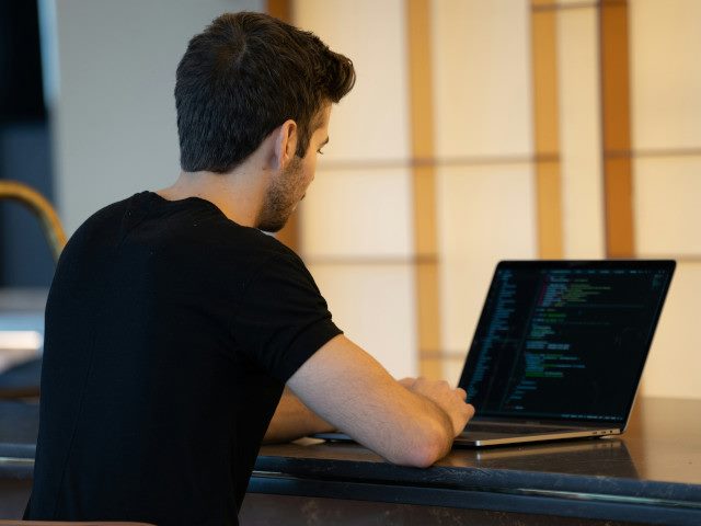 An employee writes code on a laptop computer.