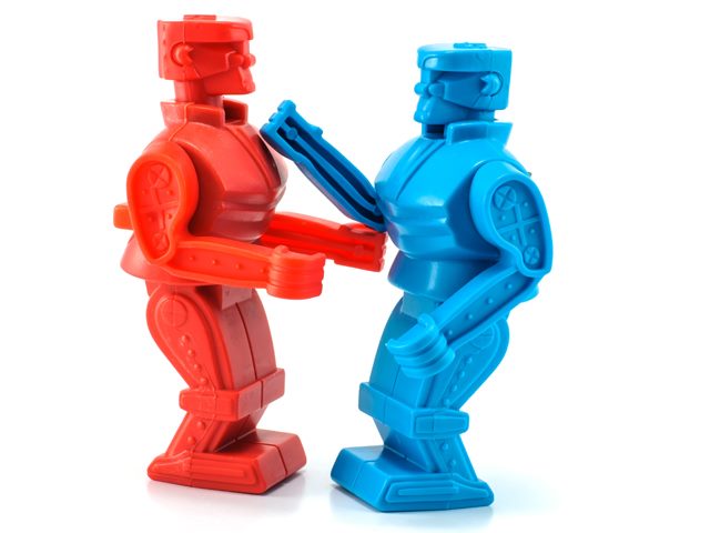A red toy robot and a blue toy robot posed as if fighting against a white background.