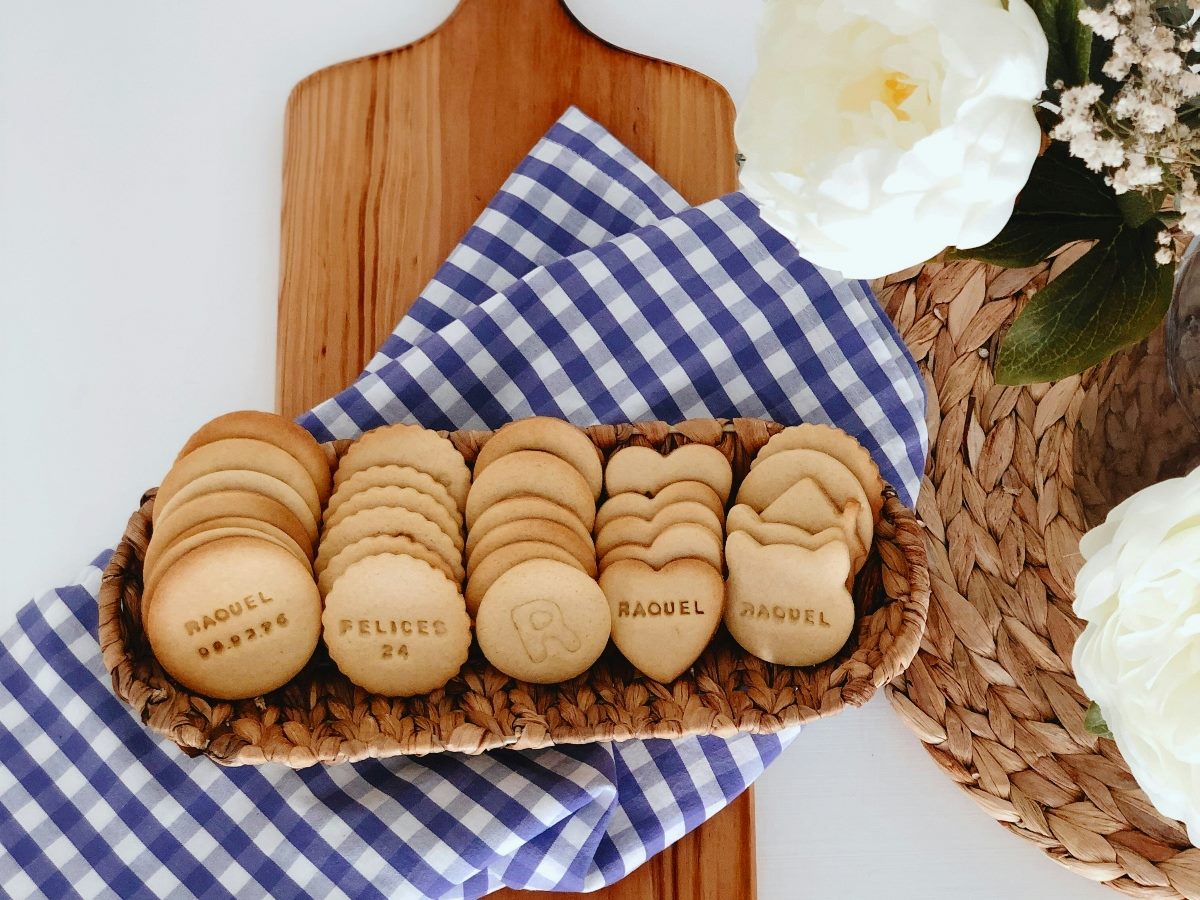 Personalized cookies with names on them on a wooden baking tool.