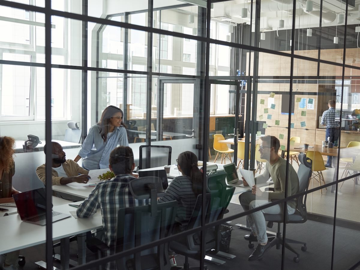 team meeting, people engaged, laptops open with AI taking minutes