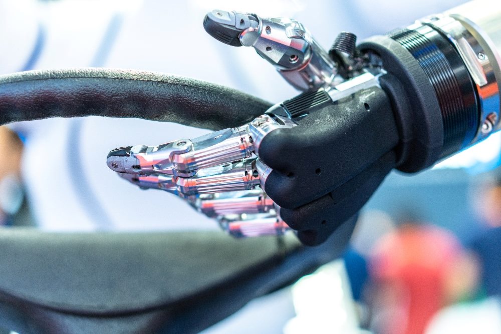A silver and black robot hand holds on to a car's steering wheel in piece about content management.