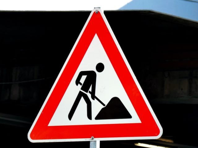 red and white construction sign against a black background