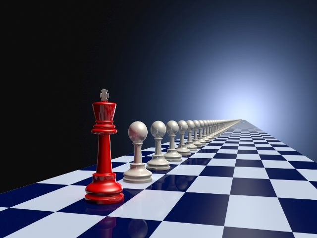 A red king Chess piece  sits before a dozen pawn on a chess board.