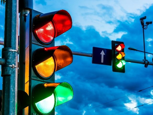 Two traffic lights hang over an urban intersection with a dramatic dark sky in the background symbolizing he needs for Generative AI Safeguards. 