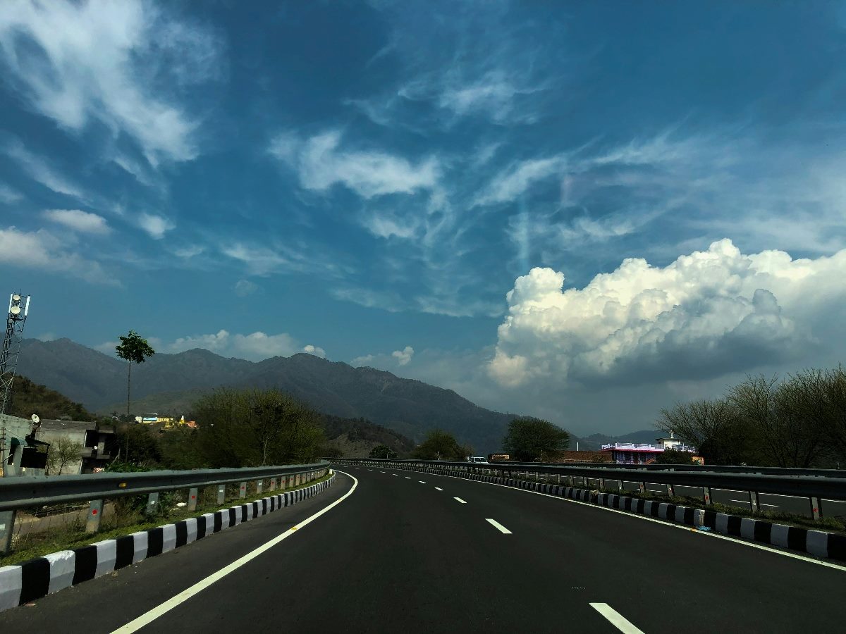 Empty road with blue skies and headed toward mountain.