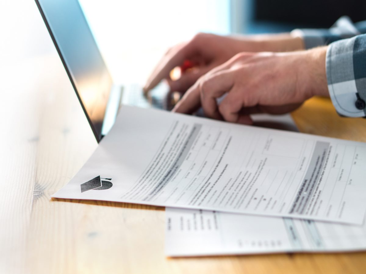 Young man writing college or university application form with laptop