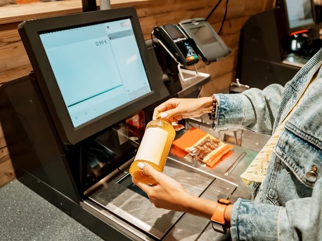 A female customer scans a bottle of juice at a self-service checkout, representing the need for customers to control their own narratives, 