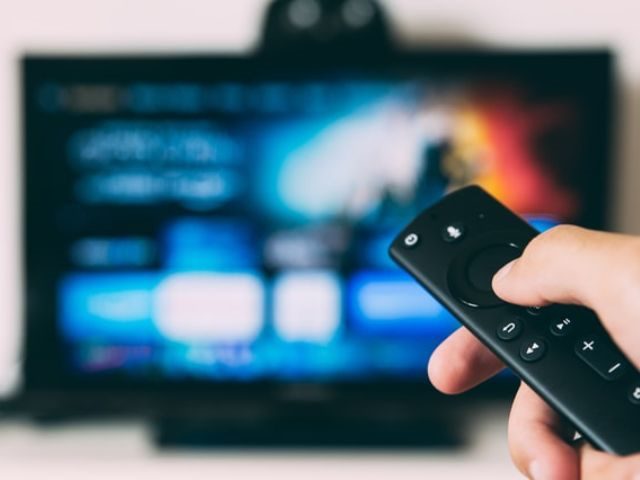 A person pointing a remote at a flat screen TV