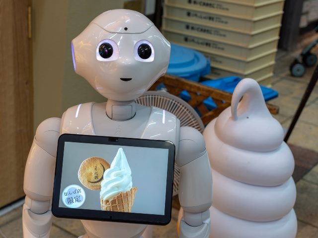 Humanoid robot at ice cream shop in Osaka, Japan, with a laptop on its chest displaying a picture of an ice-cream cone, representing customer service AI jobs.