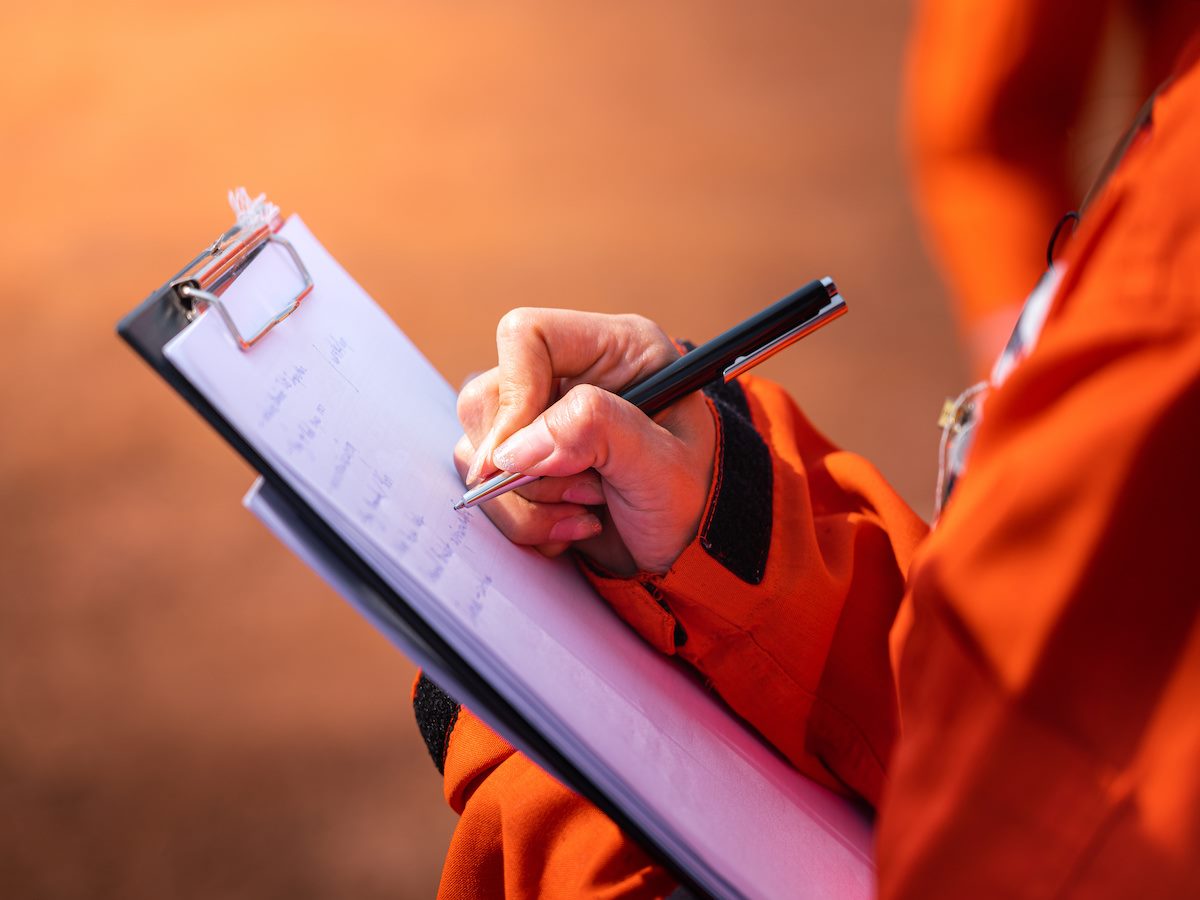A person writing a checklist on a paper