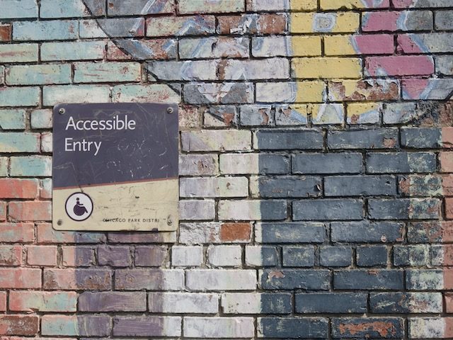 worn sign on a wall reading "Accessible Entry"
