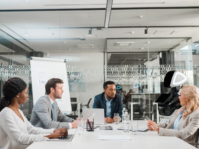 Business meeting with three humans and a robot.
