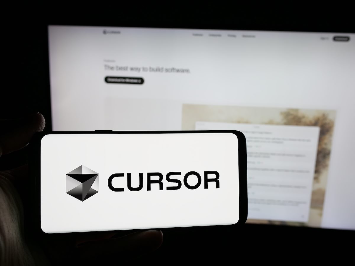 Person holding smartphone with logo of ai software company Cursor