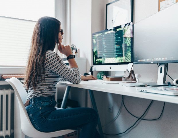 An employee works on a computer at a desk in a home office.