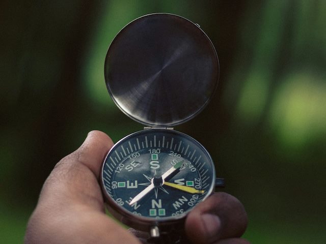 close up of a man's hand holding a compass
