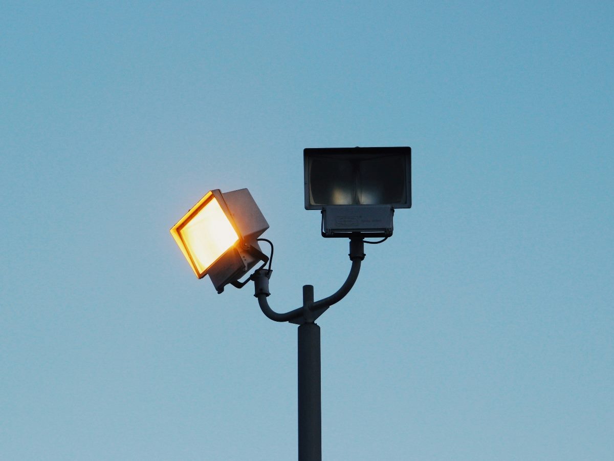 Two spotlights, one shining bright and the other not on.
