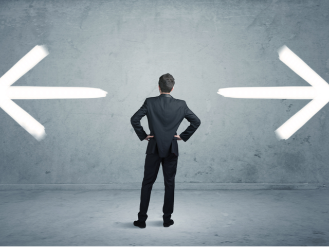 A businessman in doubt, having to shoose between two different choices indicated by arrows pointing in opposite direction